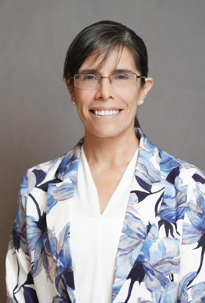 Image of Dr. Paola Cepeda. She is smiling and wearing glasses with a flower-patterned blazer.